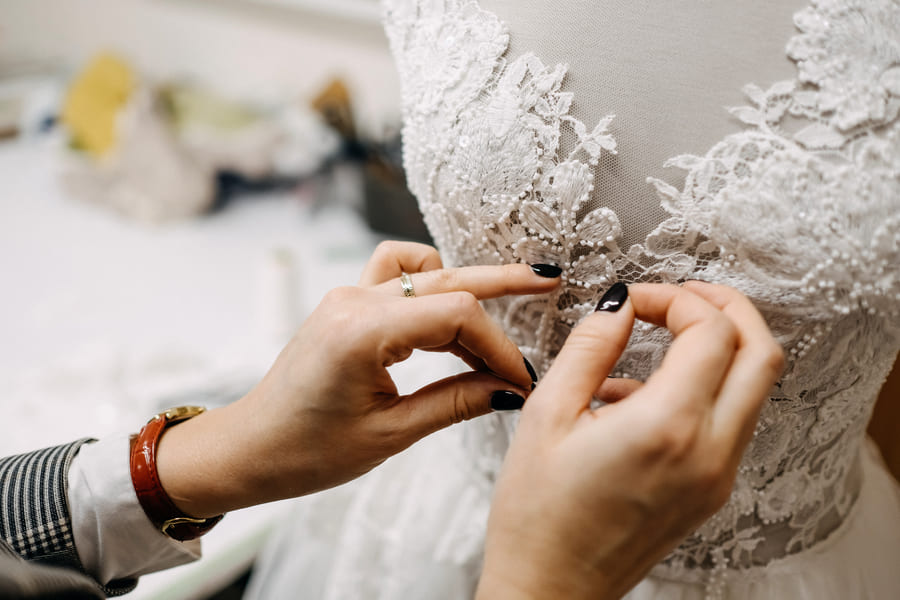 a woman is tailoring a wedding dress on a mannequin