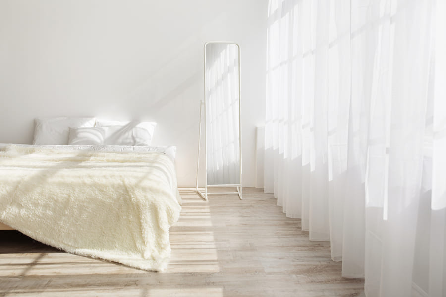 a white bedroom with a bed and white curtains